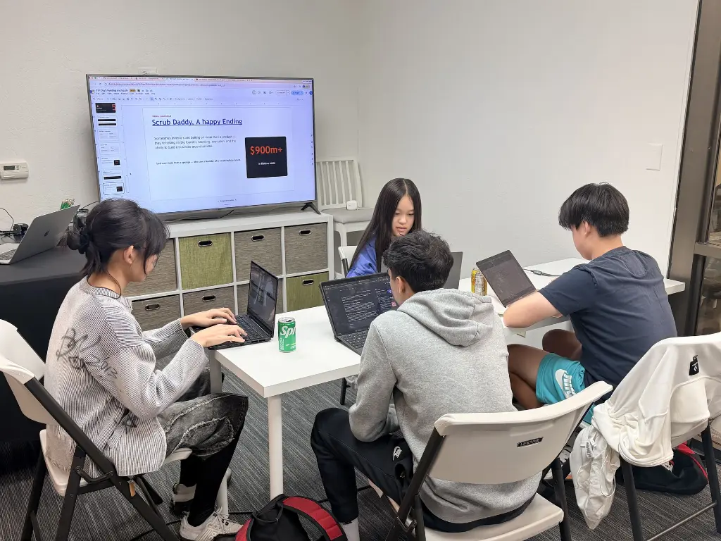 Students collaborating on a startup idea with laptops in 7EDU YEP Entrepreneurship Lab